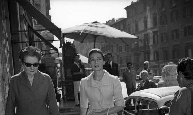 Slide 3 of 28: Ever wonder where Hepburn got her chic style? It was from her mother, Dutch Baroness Ella Van Heemstra. Here, the pair walk alongside one another in Rome.