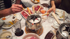 Ein gedeckter Tisch und Menschen die Fondue Chinoise essen