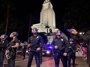 Los Angeles police officers stand outside their department as crowds block Main and First Streets in downtown Los Angeles. ((Gina Ferazzi / Los Angeles Times))