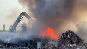 Excavator moves flaming debris