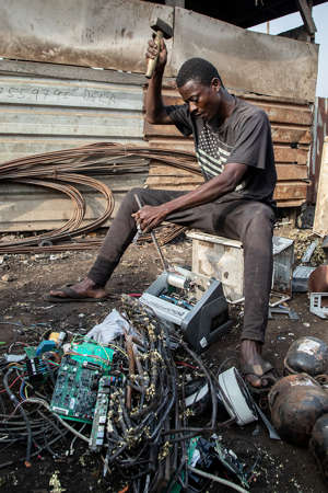 Nurideen, 35, is pictured breaking down an old battery charger inverter, which was used as backup in a solar energy storage system. He will resell valuable material like copper, lead and other metals. Materials he cannot resell will be burnt, releasing toxic gases. Photographer Sandra Weller says: ‘The number of broken solar items is increasing, but there are no regulations for professional solar waste disposal in African countries, thus it becomes part of the general e-waste problem (Picture: Sandra Weller)