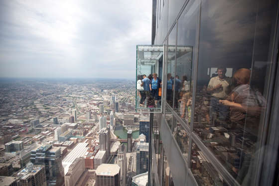 Visitors to the Sears Tower try out the ledges on the 103rd floor observation deck. The ledges are glass boxes that extend out 4.3 feet from the skydeck, giving the visitor a view straight down 1353 feet. The Sears Tower, at one point the tallest building in the world, will be renamed the Willis Tower, after being bought by Willis Group Holdings, a London-based insurance broker. - photographed: July 14, 2009