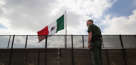 Border Patrol agent Jerry Conlin stands on the American side of the U.S.-Mexico border fence in San Ysidro, Calif.