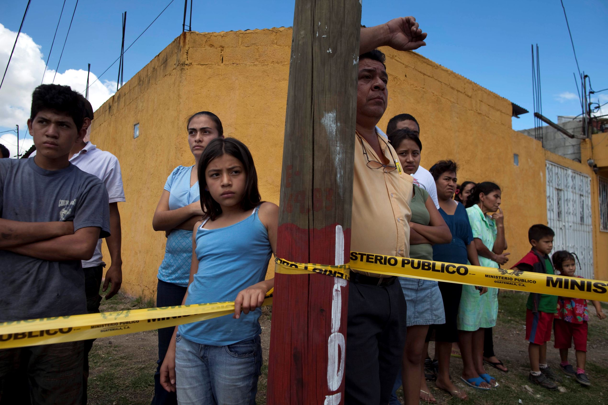 People stand behind police tape at a crime scene in Guatemala City.