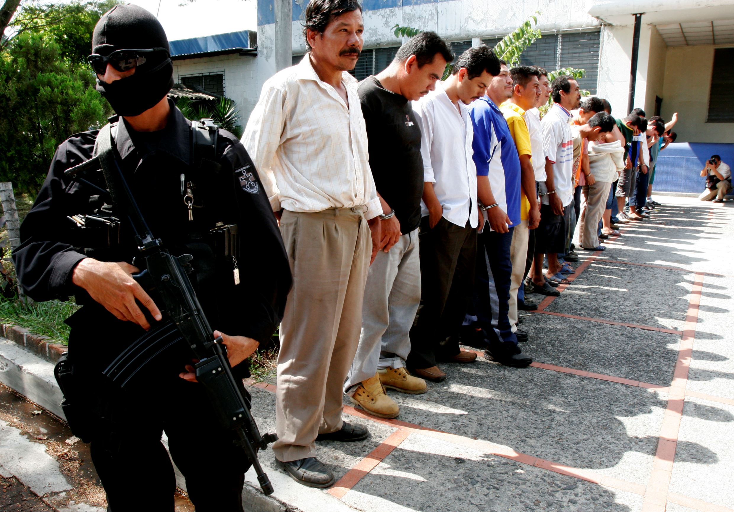 A police officer stands guard as alleged gang members are shown to the media in San Salvador.