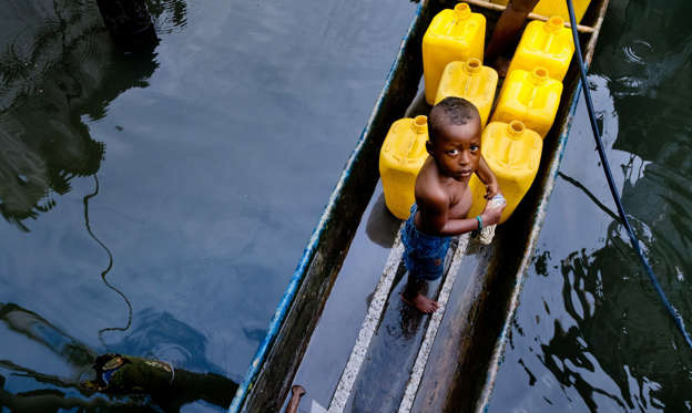 Slide 1 of 20: A Colombian boy stands in a canoe, filled by barrels of safe drinking water, inside the stilt house area in Tumaco, Colombia on June 17, 2010.