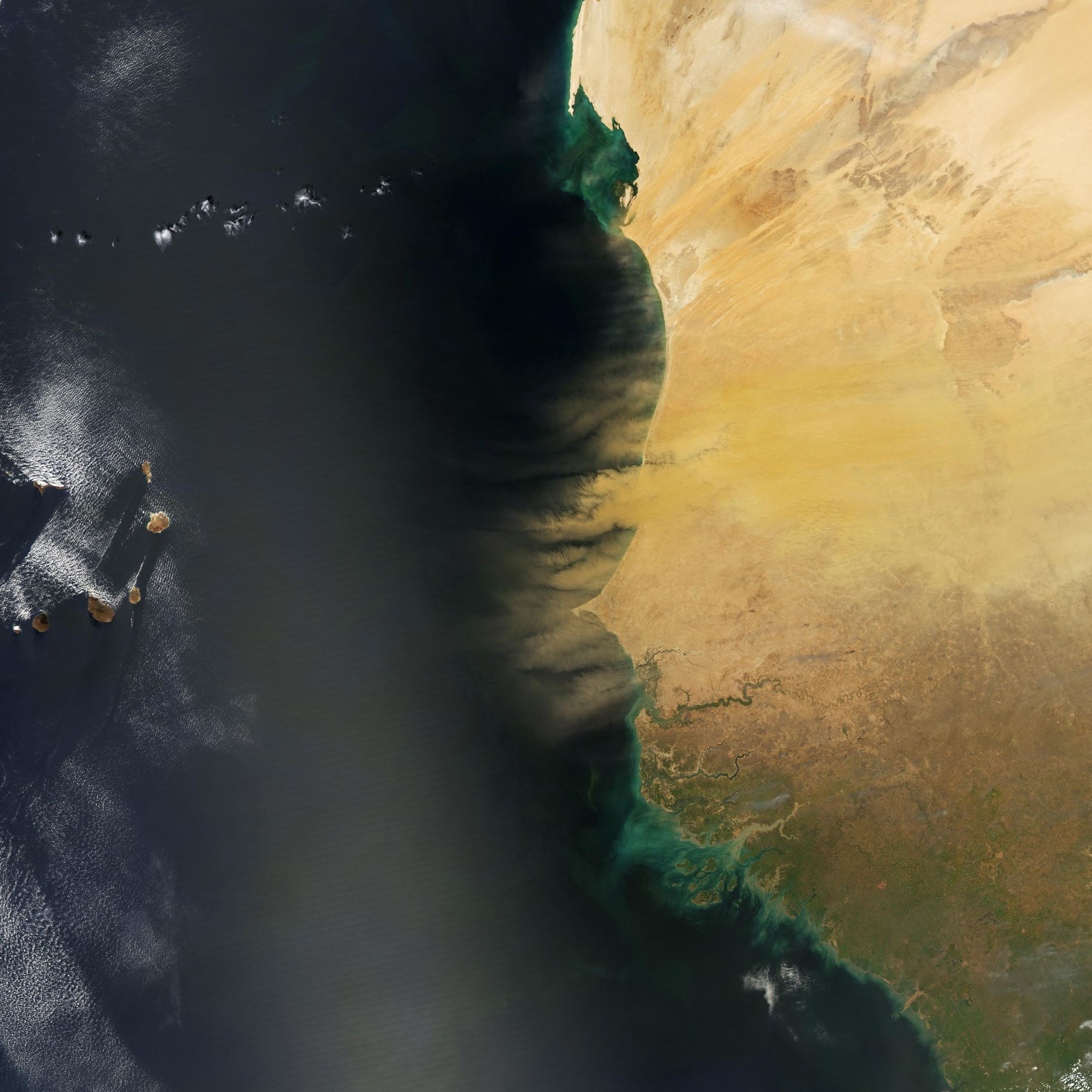 Hundreds of millions of tons of sand and dust particles are lifted from North African deserts each year and carried across the Atlantic Ocean. So much dust is kicked up that the microscopic particles amass into sweeping tan plumes that are visible to satellites. On February 26, 2015, the Moderate Resolution Imaging Spectroradiometer on NASA’s Aqua satellite observed some of that dust starting a trans-Atlantic journey. In this image, vast amounts of dust rise up from Senegal, Mauritania, and Gambia. The plumes are thick and brown, suggesting that he dust is still compact and that it probably arose close to the coast—not from a more distant location in the North African interior. Some of the dust also appears to be settling into the waters just offshore, adding to the darkening effect in the satellite view. A bit farther offshore, the water surface is brightened by sunglint, the reflection of sunlight directly back at the camera from a relatively smooth surface.