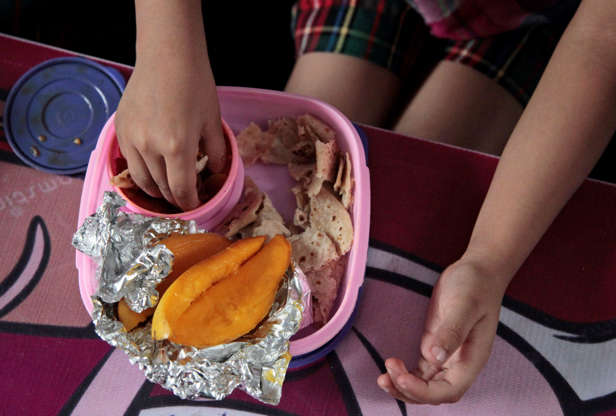 Folie 7 von 20: Baani, a 5-year-old Indian schoolgirl, eats her lunch prepared by her mother, consisting of flatbread, a turnip dish and mangoes, at a school in Jammu, India, Tuesday, May 6, 2014. Most countries seem to put a premium on feeding school children a healthy meal at lunchtime. U.S. first lady Michelle Obama is on a mission to make American school lunches healthier too, by replacing greasy pizza and french fries with whole grains, low fat protein, fresh fruit and vegetables. (AP Photo/Channi Anand)