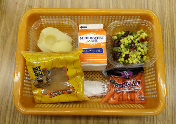 Folie 4 von 20: A school lunch featuring a grilled cheese sandwich on whole grain bread is served with a southwestern-style corn salad, fresh carrots and either canned pears or apple sauce Monday, May 5, 2014, at Mirror Lake Elementary School in Federal Way, Wash., south of Seattle. on this day, students could choose between this lunch or a green salad entree option featuring low-sodium chicken, a whole-grain roll, fresh red peppers, and cilantro dressing. (AP Photo/Ted S. Warren)