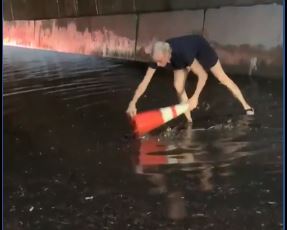 Woman clears clogged drains during flash floods