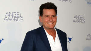 Charlie Sheen holding a sign posing for the camera: When it comes to the Hollywood blacklist, there is no one more synonymous than Charlie Sheen.  Once the highest paid television actor in the world in ‘Two and a Half Men’, Sheen’s ‘Anger Management’ show was canceled in 2014 and he has had very few roles since.