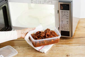 woman heating leftovers in microwave