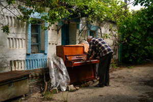 Local resident Anatolii Virko plays a piano outside a house likely damaged after a Russian bombing in Velyka Kostromka village, Ukraine, Thursday, May 19, 2022.