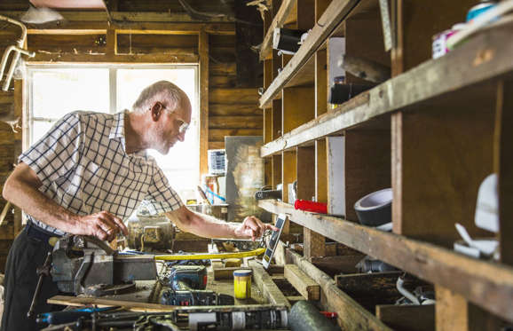 Confident senior carpenter sitting in workshop.