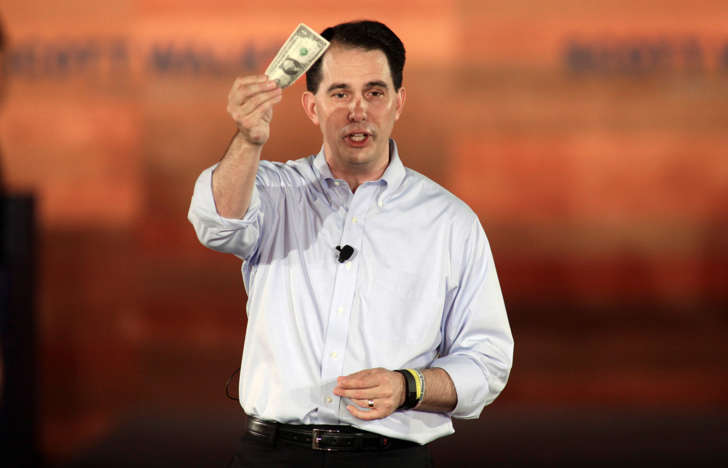 Republican presidential candidate and Wisconsin Governor Scott Walker waves a U.S. one dollar bill as he formally announces his campaign for the 2016 Republican presidential nomination during a kickoff rally in Waukesha, Wisconsin, on July 13, 2015.