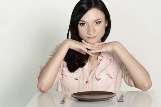 Brunette woman sitting in front of an empty dish