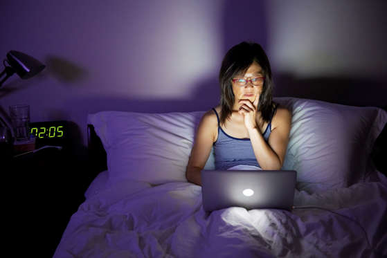 Woman working late on laptop in bed