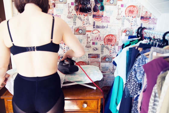Cropped rear view of young woman in underwear ironing in dressing room