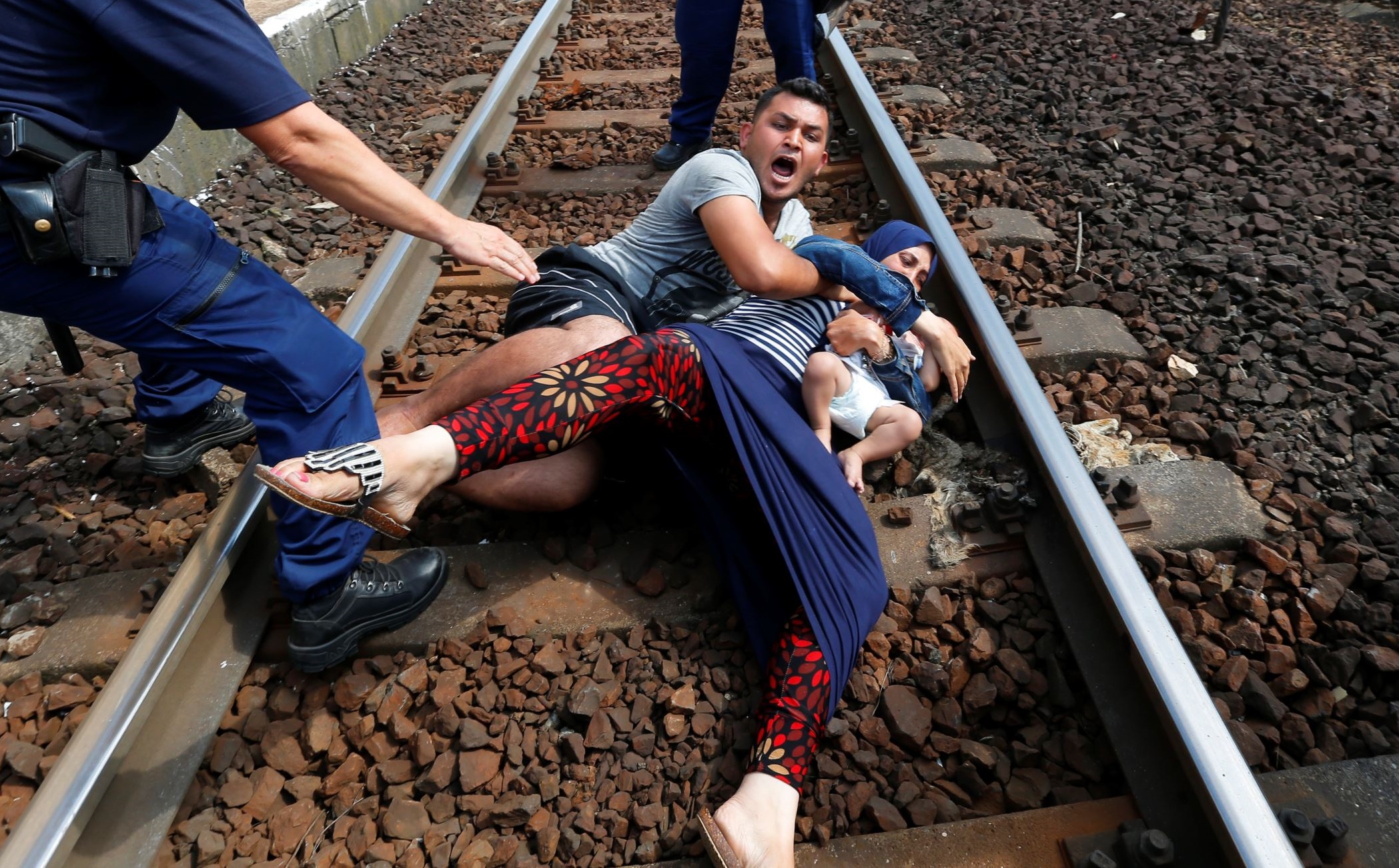 Hungarian policemen stand by the family of migrants as they wanted to run away a...