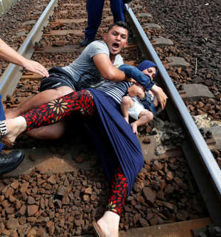 Hungarian policemen stand by the family of migrants as they wanted to run away a...