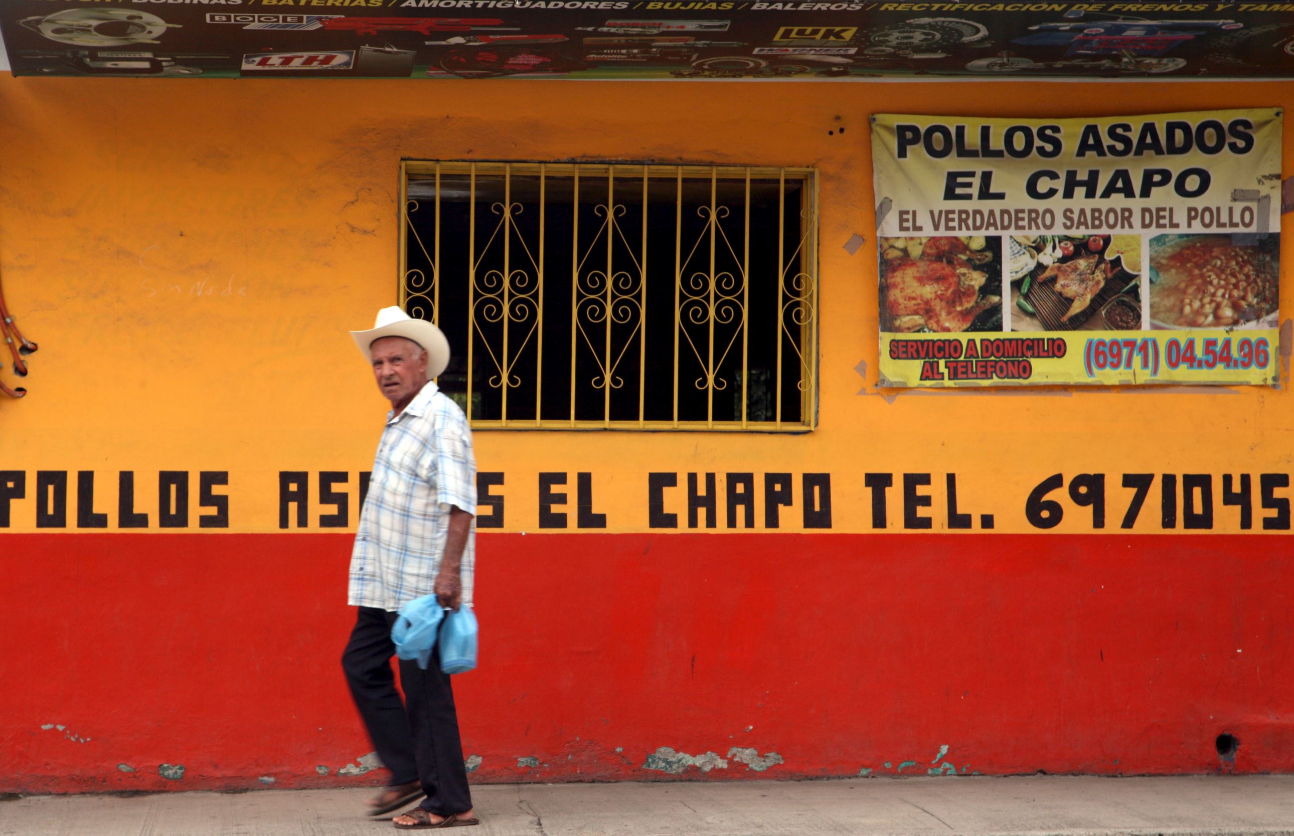 A resident walks past the "Chapo" roast chicken restaurant near the main plaza of Joaquin "El Chapo" Guzman's hometown in the municipality of Badiraguato, in the Mexican state of Sinaloa on Friday.