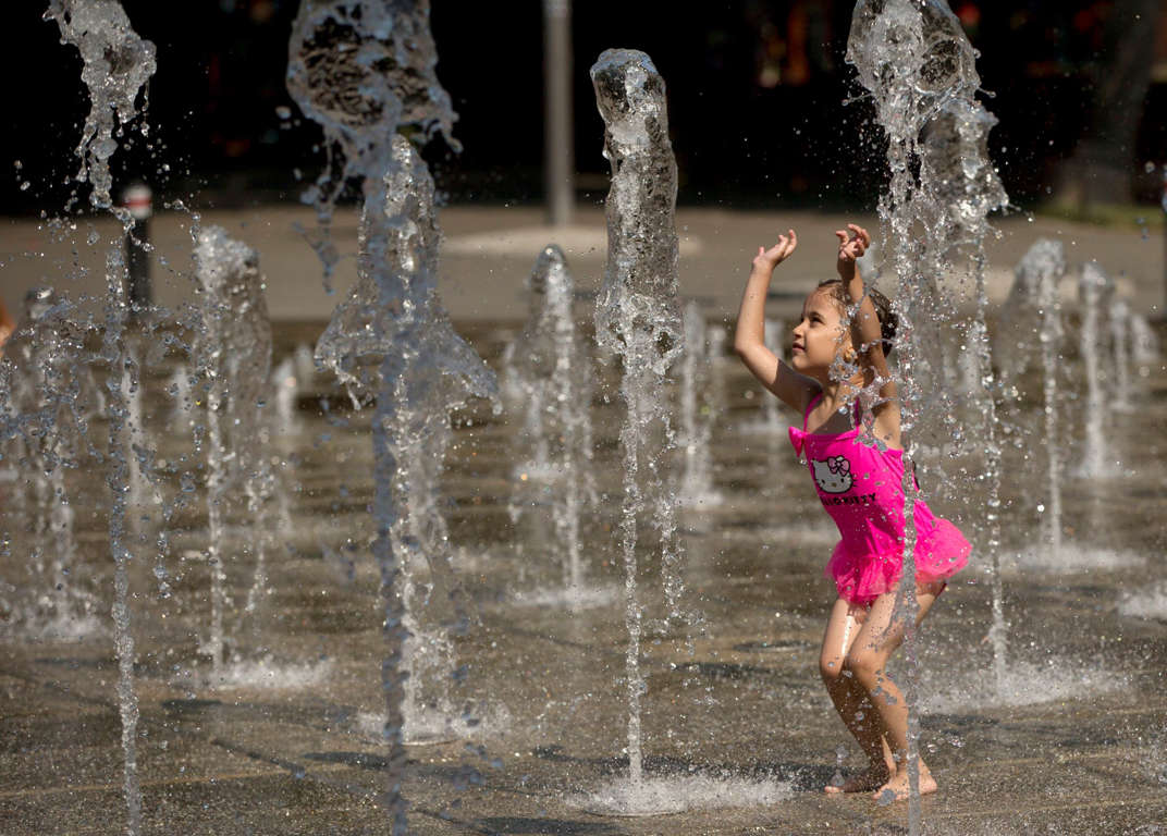 A girl plays at a fountain in Bucharest, Romania, Wednesday, July 8, 2015. Large areas of Romania are affected by a heat wave with temperatures higher than 37 degrees Celsius or 98.6 Fahrenheit.