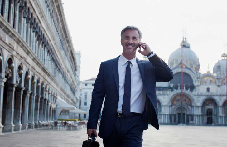 Businessman talking on cell phone and walking through St. Mark&#39;s Square in Venice.