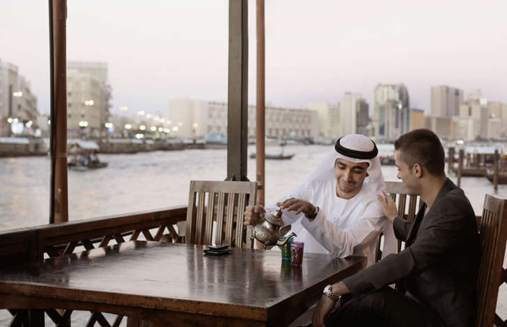 Two men drinking tea in Middle Eastern country.