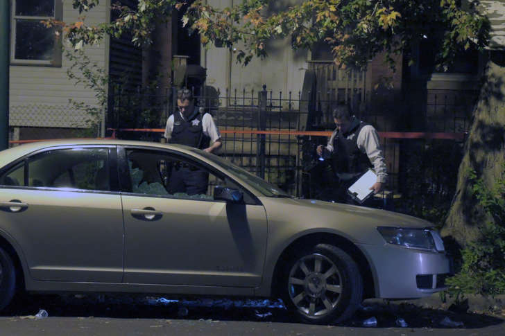 Police officers investigate the scene of the shooting in the 5200 block of South Justine Street where four people were wounded late Sunday evening on Sept. 27, 2015 in Chicago.