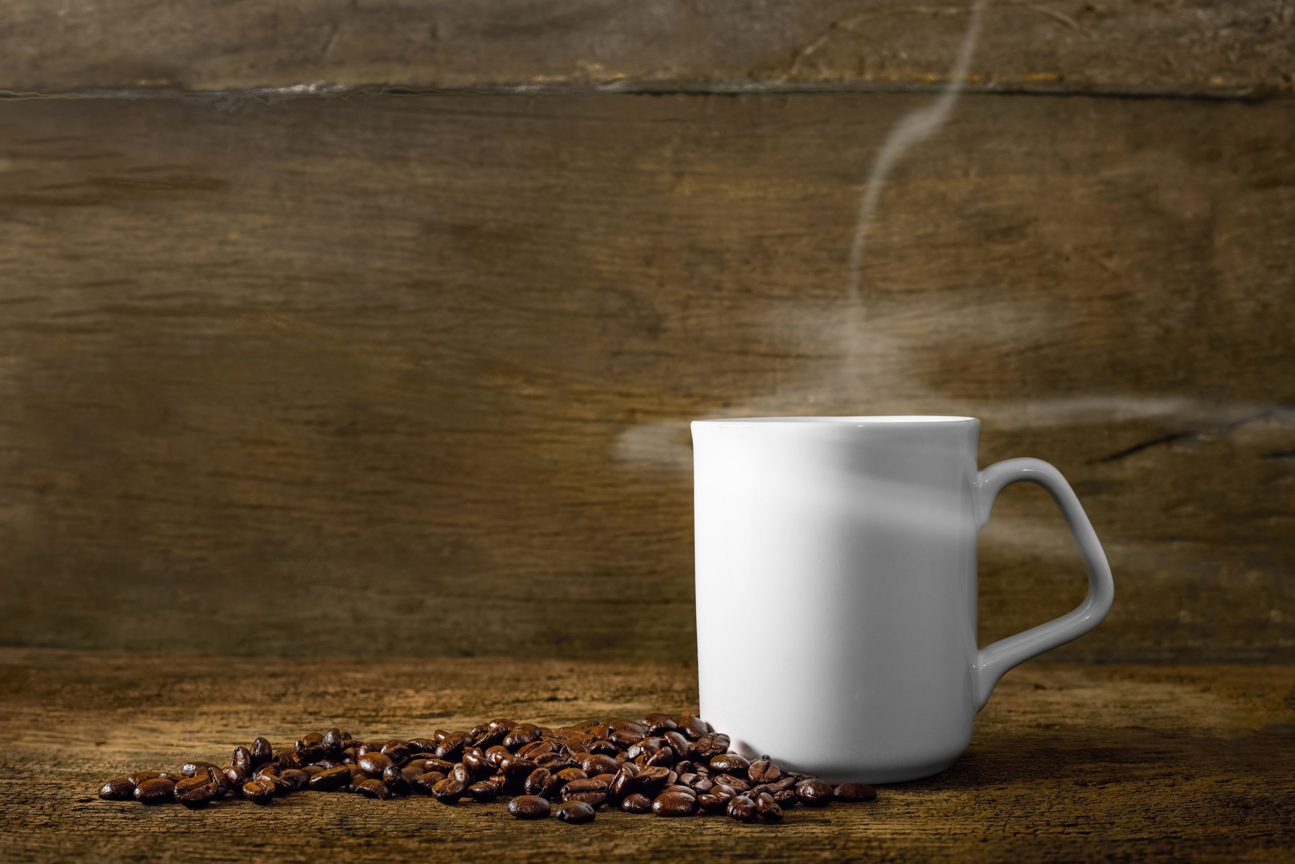 Cup of coffee with smoke and coffee beans on old wooden background.