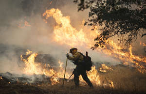 A firefighter lights a back burn along Highway 29 north of Middletown, Calif., S...