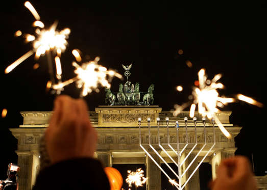 Members of Berlin's Jewish community and residents of Berlin light sparklers in front of the menorah at the Brandenburg Gate in Berlin, Sunday, Dec. 21, 2008 to commemorate the Jewish holiday Hanukkah. (AP Photo/Herbert Knosowski)