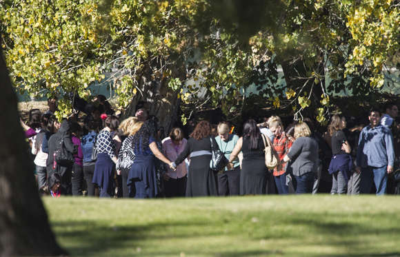 Evacuated workers pray on the San Bernardino Golf Course across the street from a mass shooting at the Inland Regional Center in San Bernardino, Calif., on Wednesday, Dec. 2, 2015.