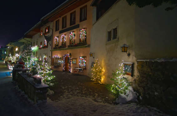 Gruyeres, Switzerland - January 2, 2015: Night view of the main street in the swiss village Gruyeres, Switzerland. The medieval town is an important tourist location and gives its name to the well-known Gruyere cheese
