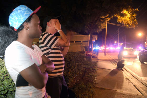Jermaine Towns, left, and Brandon Shuford wait down the street from a multiple shooting at a nightclub in Orlando, Fla., Sunday, June 12, 2016. Towns said his brother was in the club at the time. A gunman opened fire at a nightclub in central Florida, and multiple people have been wounded, police said Sunday.