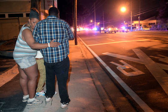 Bystanders wait down the street from a multiple shooting at the Pulse nightclub in Orlando, Fla., Sunday, June 12, 2016. A gunman opened fire at a nightclub in central Florida, and multiple people have been wounded, police said Sunday.