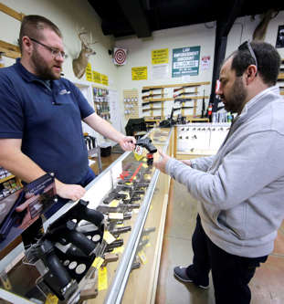 Mike Howse, left, helps David Foley as he shops for a handgun at the Spring Guns...