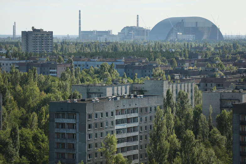 The former Chernobyl nuclear power plant, including destroyed reactor four (C), as well as the New Safe Confinement structure (R) that will one day enclose the remains of reactor four, stand behind the abandoned city of Pripyat on September 30, 2015 near Pripyat, Ukraine.