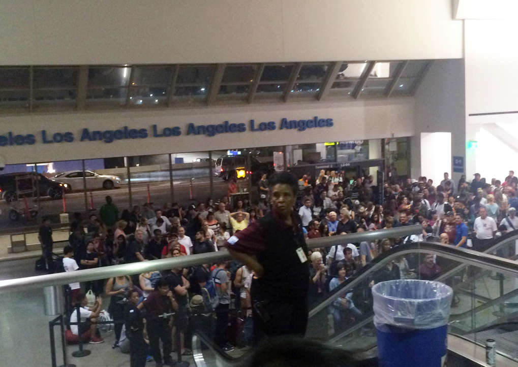A crowd of people wait in Terminal 1 where passengers were being rescreened by security at Los Angeles International Airport after reports that a gunman opened fire Sunday, Aug. 28, 2016.