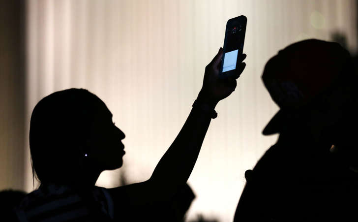 A protester uses her phone to make a video of the proceedings during another night of protests over the police shooting of Keith Scott in Charlotte, North Carolina, U.S. September 24, 2016.
