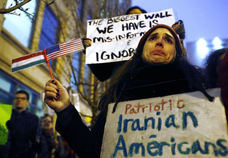 Becky Perlman, an Iranian immigrant holds back tears as she holds a sign and an Iranian and American flag during a protest against President Donald Trump's plan to build a border wall along the United States and Mexico border on January 26, 2017 in Chicago, Illinois.