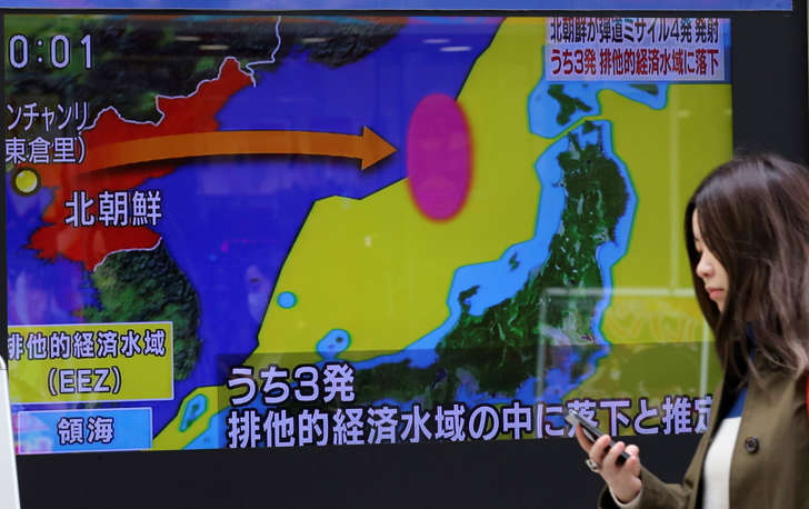 A woman walks past a screen showing a TV news on a missile firing by North Korea with a map of Japan and North Korea in Tokyo, Monday, March 6, 2017.