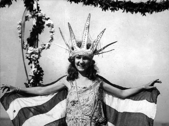 Slide 6 of 12: 1921:  Margaret Gorman from Washington D.C. smiles, wearing a large Statue of Liberty crown and a striped cape, as the first Miss America, Atlantic City, New Jersey. The Miss America Pageant was first devised as a way to extend the summer tourist season in the beach-front town.  (Hulton Archive/Getty Images)