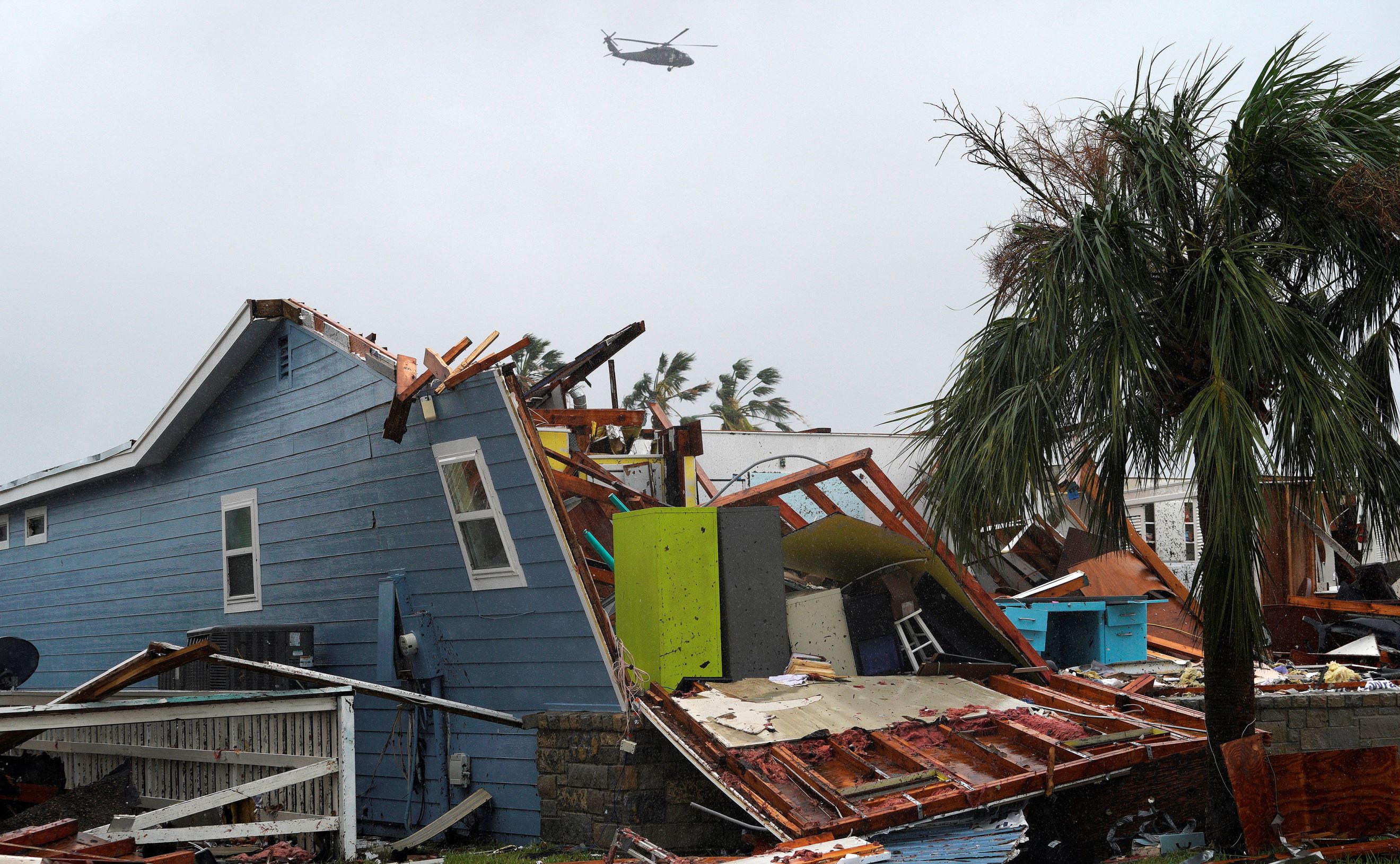Slide 7 of 77: A military helicopter flies over a destroyed house after Hurricane Harvey struck in Rockport, Texas, August 26, 2017.