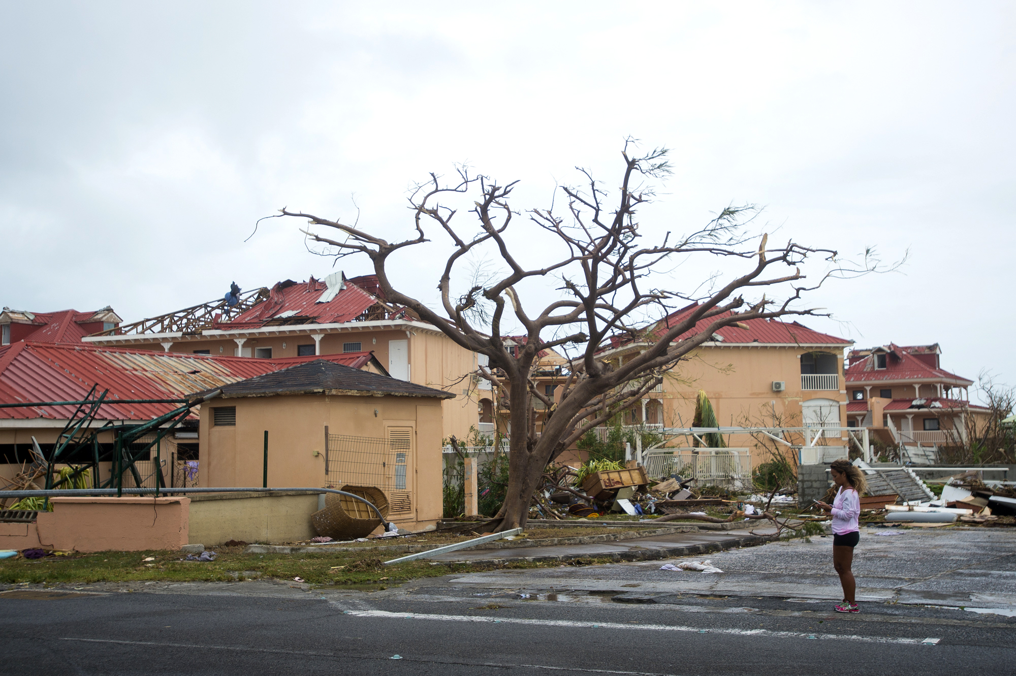 TOPSHOT - A woman stands near damaged homes in Marigot, near the Bay of Nettle, on the French Collectivity of Saint Martin, on September 6, 2017, after the passage of Hurricane Irma. France, the Netherlands and Britain on September 7 sent water, emergency rations and rescue teams to their stricken territories in the Caribbean hit by Hurricane Irma, which has killed at least 10 people. The worst-affected island so far is Saint Martin, which is divided between the Netherlands and France, where eight of the 10 confirmed deaths took place. / AFP PHOTO / Lionel CHAMOISEAU (Photo credit should read LIONEL CHAMOISEAU/AFP/Getty Images)