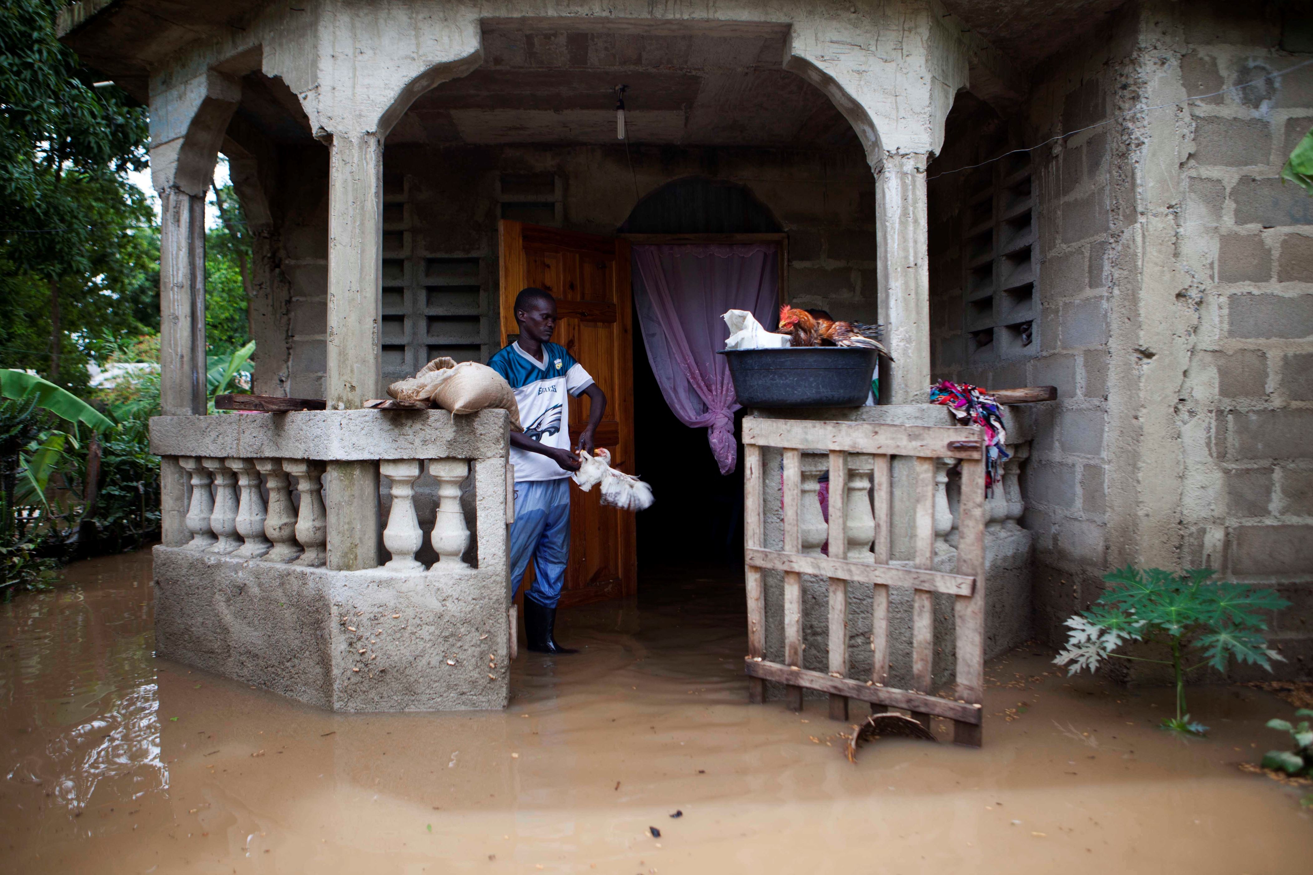A man salvages items from his home flooded by heavy rains brought on by Hurricane Irma, in Fort-Liberte, Haiti, Friday Sept. 8, 2017. Irma rolled past the Dominican Republic and Haiti and battered the Turks and Caicos Islands early Friday with waves as high as 20 feet (6 meters). ( AP Photo/Dieu Nalio Chery)