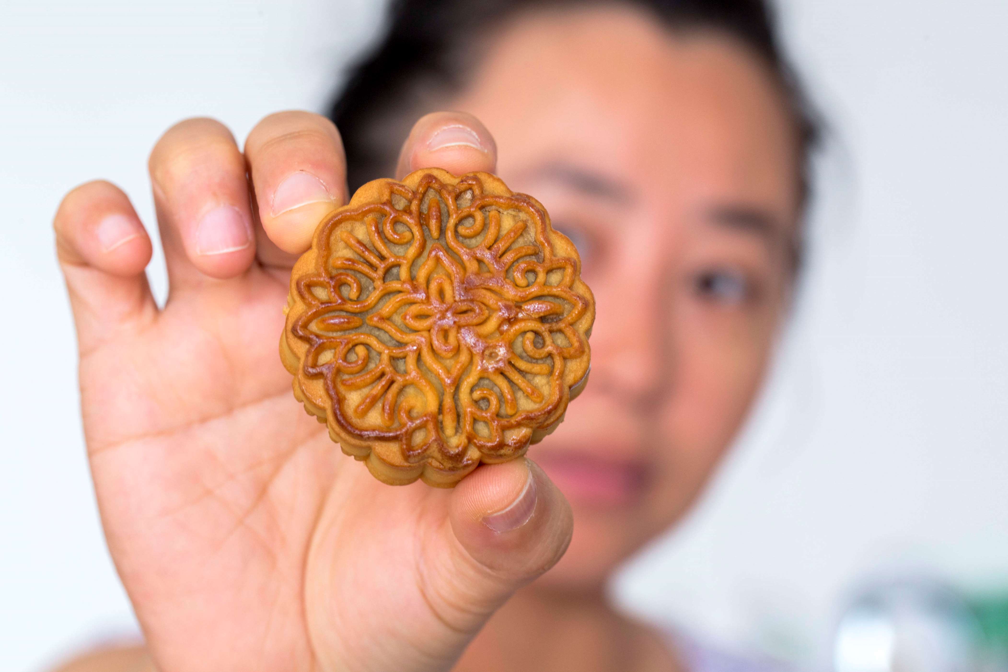 BEIJING, CHINA - 2017/09/24: Hand holding a moon cake, arranged for photography. Mid-autumn festival is a Chinese traditional holiday and the moon cake is the main folk food of the holiday. Every year, the questions of food safety, over packaging and high prices are the hot topics about the moon cakes.