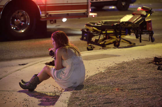 Slide 2 of 16: A woman sits on a curb at the scene of a shooting outside of a music festival along the Las Vegas Strip, Monday, Oct. 2, 2017, in Las Vegas. Multiple victims were being transported to hospitals after a shooting late Sunday at a music festival on the Las Vegas Strip.