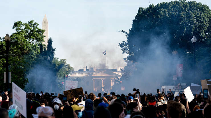 a crowd of people with smoke coming out of it: Police advance on protesters outside the White House to clear a path for President Trump to walk to St. Johns church in Washington on Monday