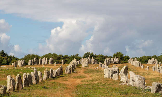 Slide 2 of 32: Are these megaliths the petrified remains of a Roman legion turned to stone by the wizard Merlin? So local legend would have us believe, but the truth could be just as fascinating. Near the village of Carnac in Brittany, northern France, a vast area of 100 acres (40ha) holds around 3,000 standing stones marching into the distance as far as the eye can see. Some stones are placed in regimented lines, others in circles and some on top of another to form tombs.